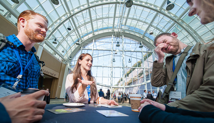 A group of conference attendees have a discussion under the glass dome at the Washington State Convention Center in Seattle.