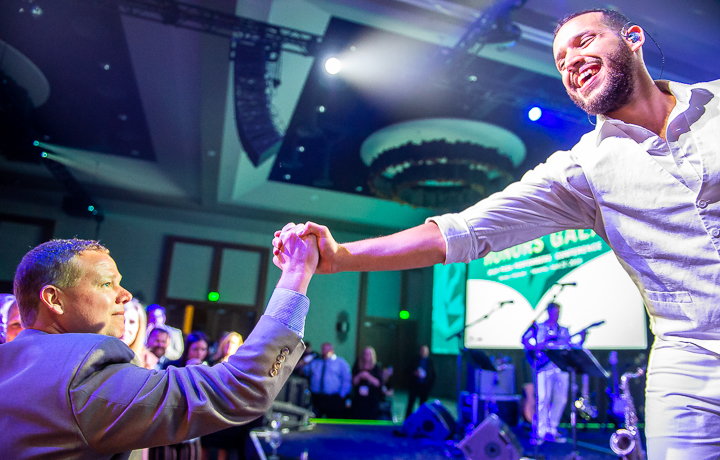 Celebrity House Band member David Posso gets a congratulatory handshake from an audience member at a corporate conference.