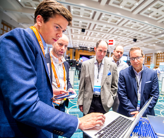 An exhibitor at HSMAI's trade show demonstrates his company's software to a group of attendees.