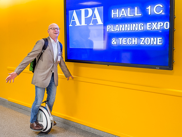 An attendee arrives at the American Planning Association's Planning Expo at the Javits Center in New York City on an electric unicycle.