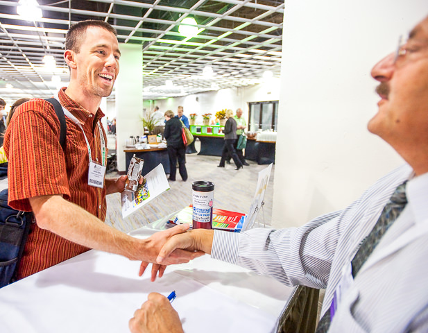 A Green Schools conference attendee shakes hands with a trade show vendor.