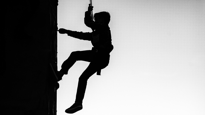 A silhouette of a sales conference attendee ascending a climbing wall at the event's Welcome party.