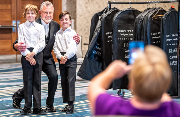 Two young boys take a break from tuxedo fitting to pose for a photo with their grandfather, who was getting inducted into a corporate Hall of Fame.