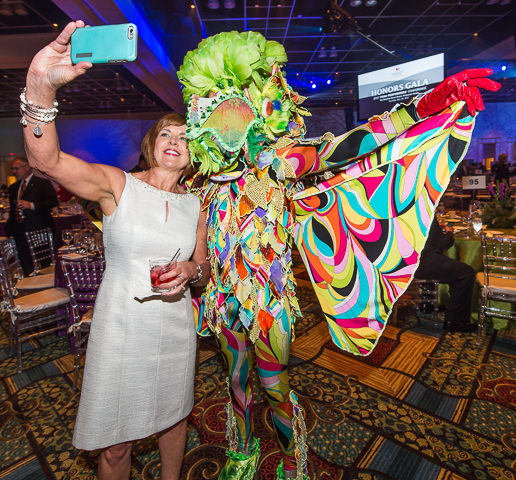 A corporate Honors Gala attendee poses for a selfie with a costumed performer.