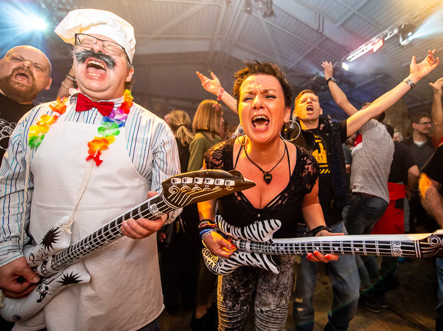 Attendees to the Marillion Weekend in Port Zelande, Netherlands, sing along and play air guitar at a concert after-party.