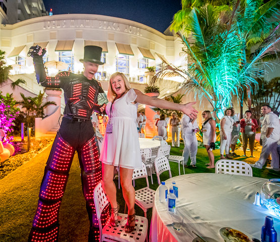 A corporate party attendee at the Loews Miami Beach Hotel poses with a stilt walking performer.