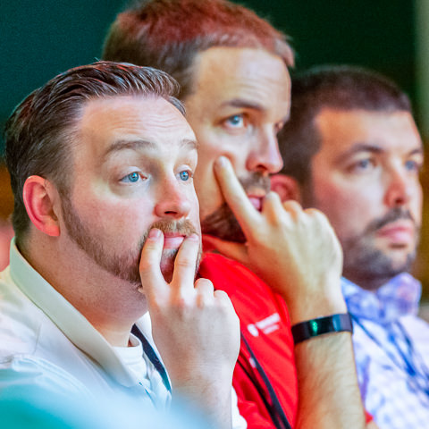 At a business conference for financial advisors in Minneapolis, three attendees listen intently to a speaker.
