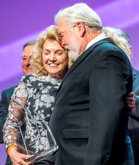 A Great Clips executive is congratulated by her husband after receiving the company's Hall of Fame award at their biannual convention in Minneapolis.