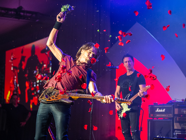Rick Springfield strums his guitar with a bouquet of roses creating a shower of rose petals.
