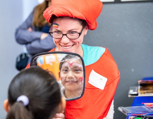 A young girl checks the face painting she got from a conference attendee volunteering at an activity center in San Francisco's Tenderloin district.