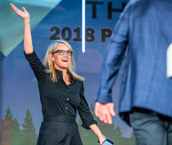 Mel Robbins greets the audience as she arrives on stage for a keynote speech.