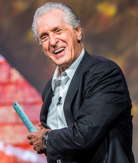 NBA Coach Pat Riley shares a joke on stage while speaking to a conference in South Florida.