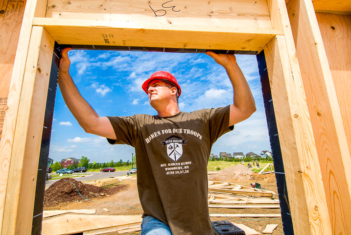 A volunteer member of a Homes for Our Troops 'Build Brigade' helps frame out a new home for a wounded veteran.