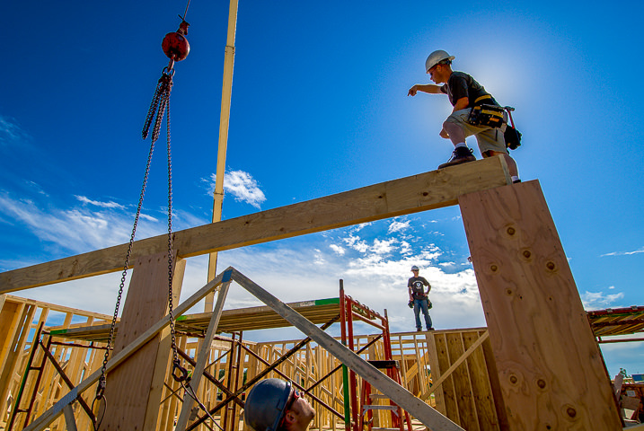 A construction worker directs a beam lift at a residential build project.