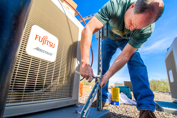 A technician installs a Fujitsu Airstage compressor unit on the roof of a men's shelter in St Paul, MN.