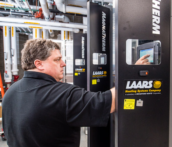 A technician programs a Laars Magnatherm commercial boiler in a newly constructed high school.