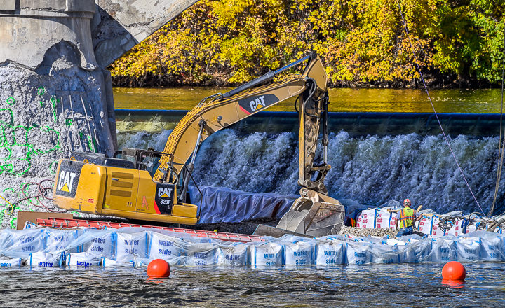 An backhoe works inside a coffer dam as part of the refurbishment of the 3rd Avenue Bridge in downtown Minneapolis.