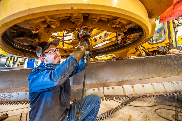 A county employee in northern Minnesota performs maintenance work on one of the county's road graders.