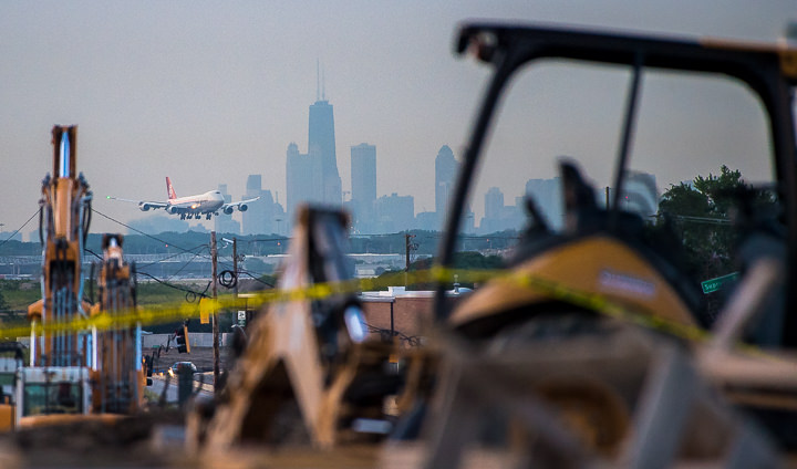 A 747 cargo plane lands in the dawn light at O'Hare Airport in Chicago, as road equipment being used to construct a new western access road for the airport sits in the foreground.