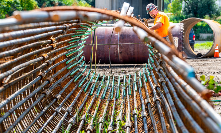A worker puts the finishing touches on a rebar cage to be used in creating a concrete pier for a new highway bridge.